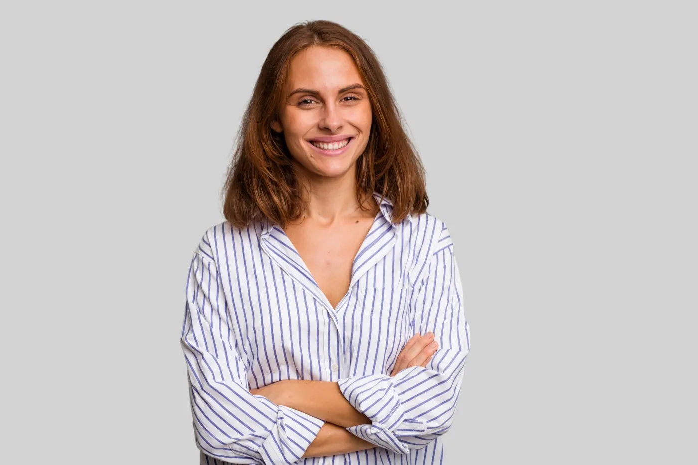 A smiling woman in a striped shirt with her arms folded