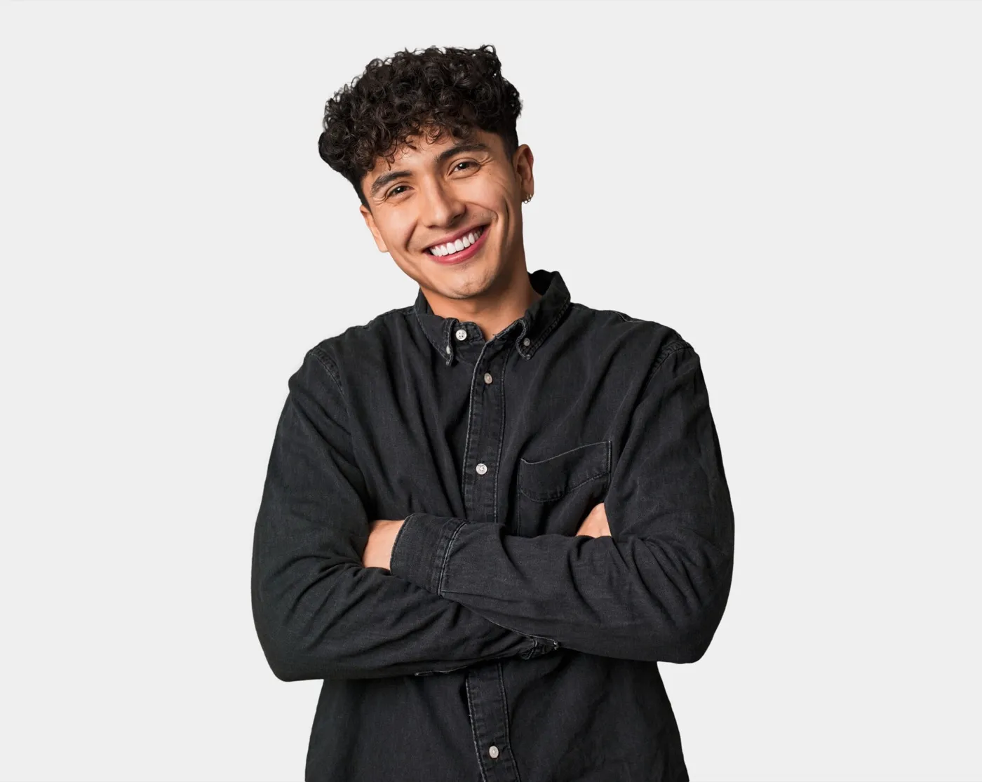 A smiling young man in a black shirt with his arms folded
