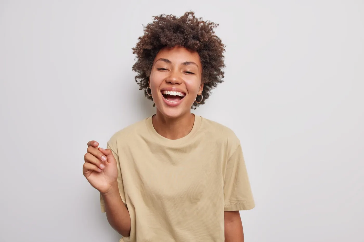 A laughing woman in a beige T-shirt