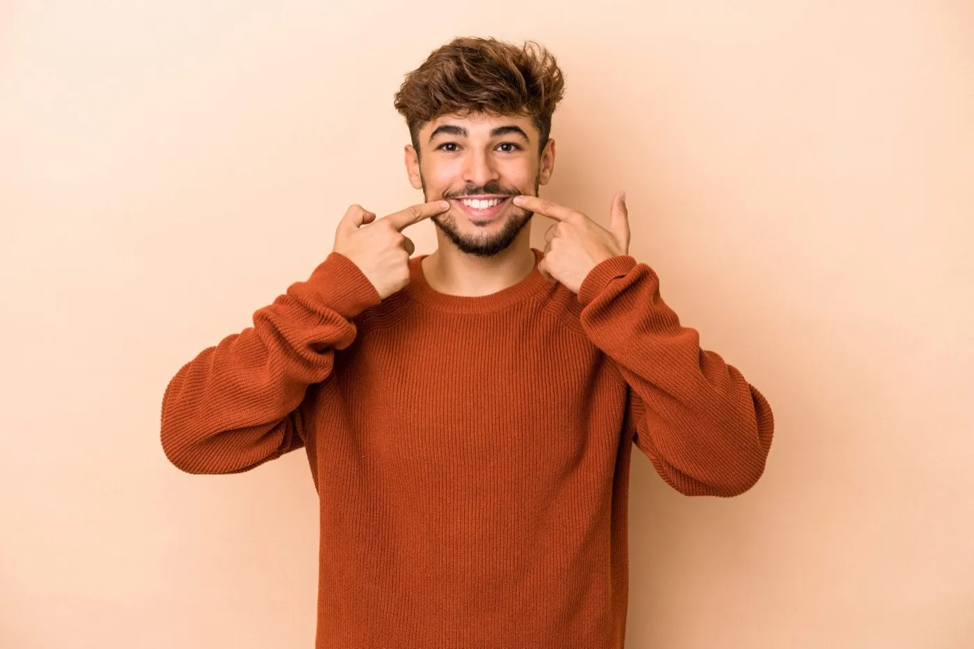 A smiling man pointing at his smile