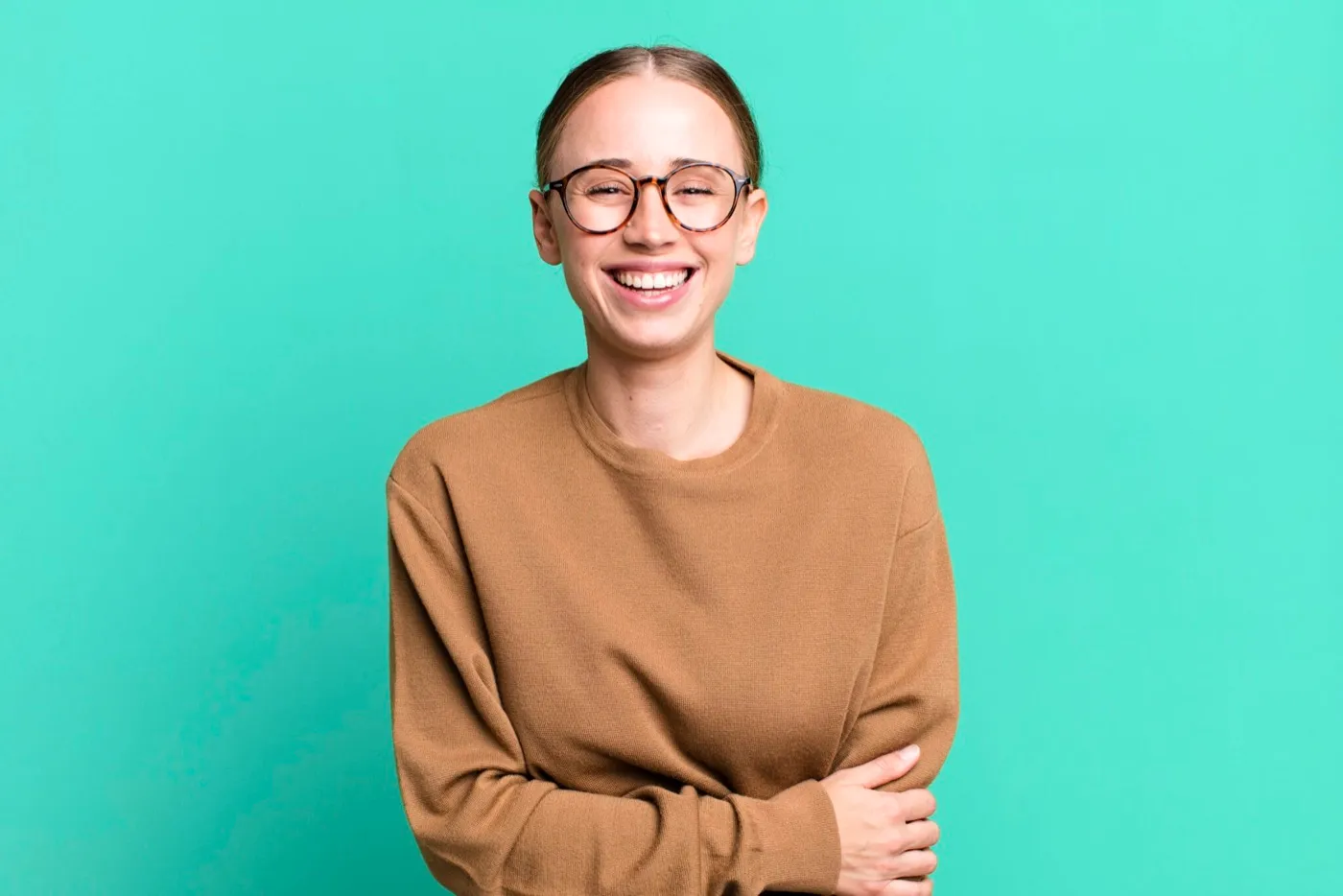 A smiling woman in glasses and a brown jumper