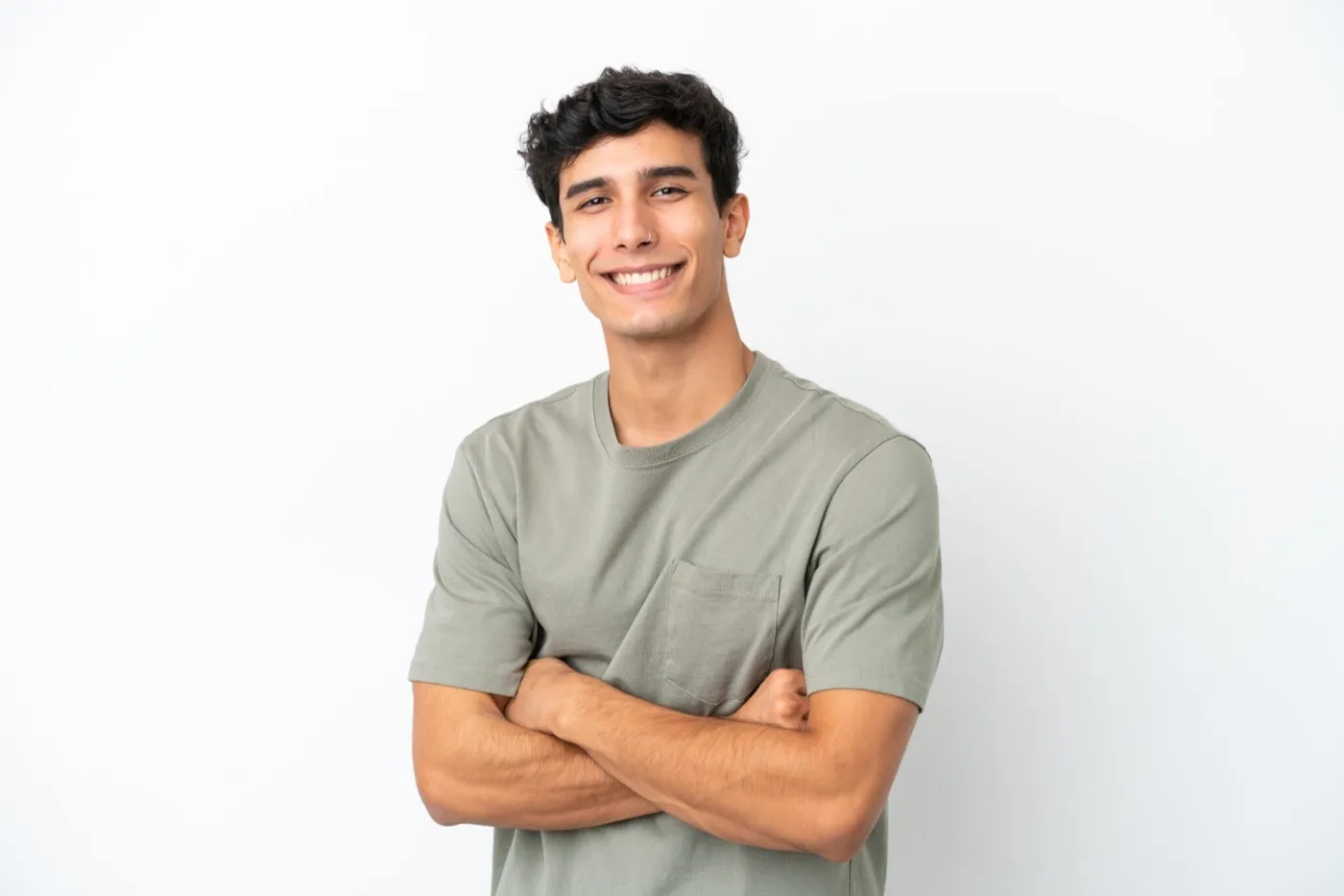 A smiling young man in a grey T-shirt with his arms folded