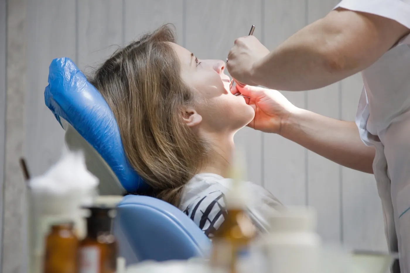 A dentist examining a woman's teeth in the dental chair