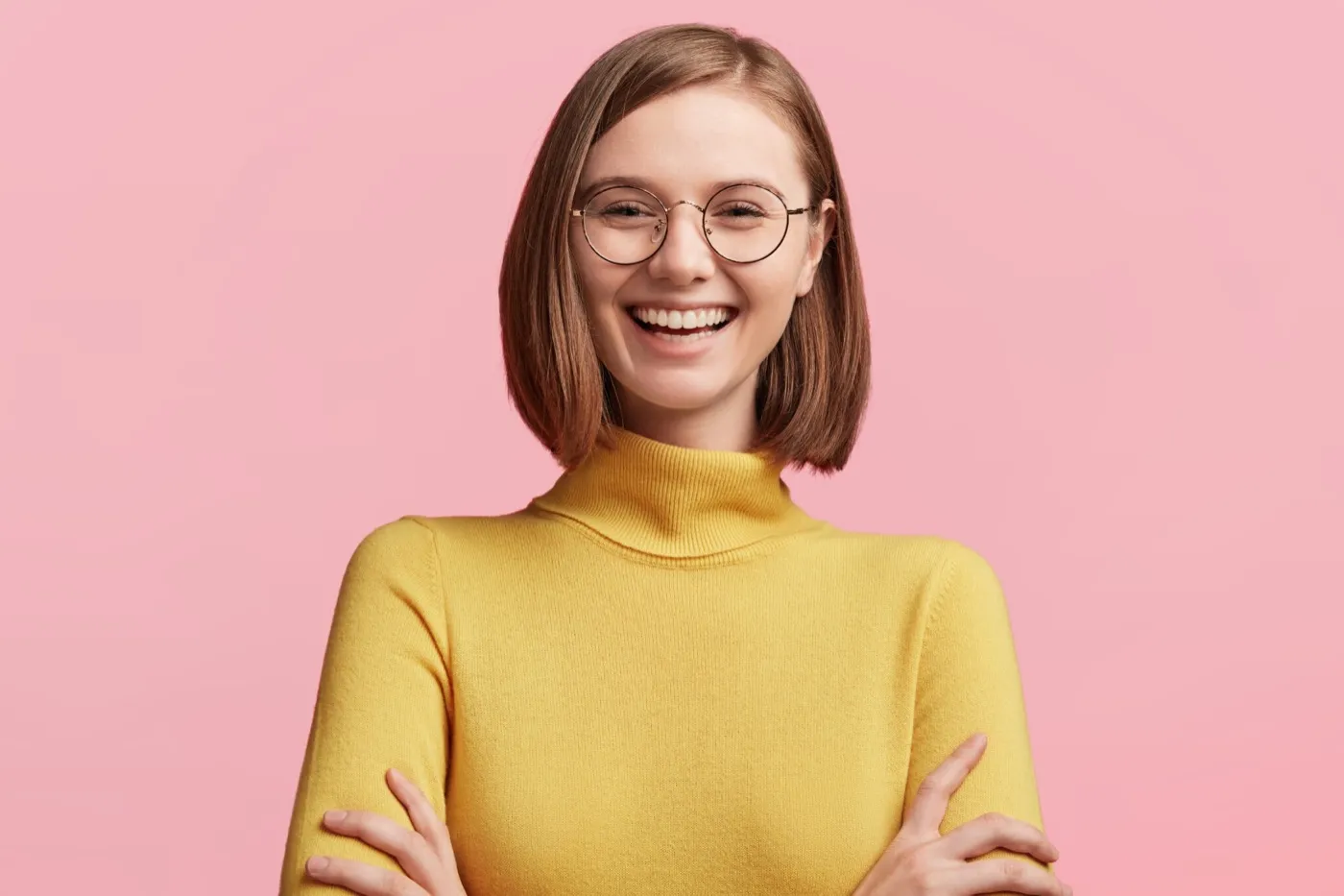 A smiling woman in round glasses and a yellow jumper
