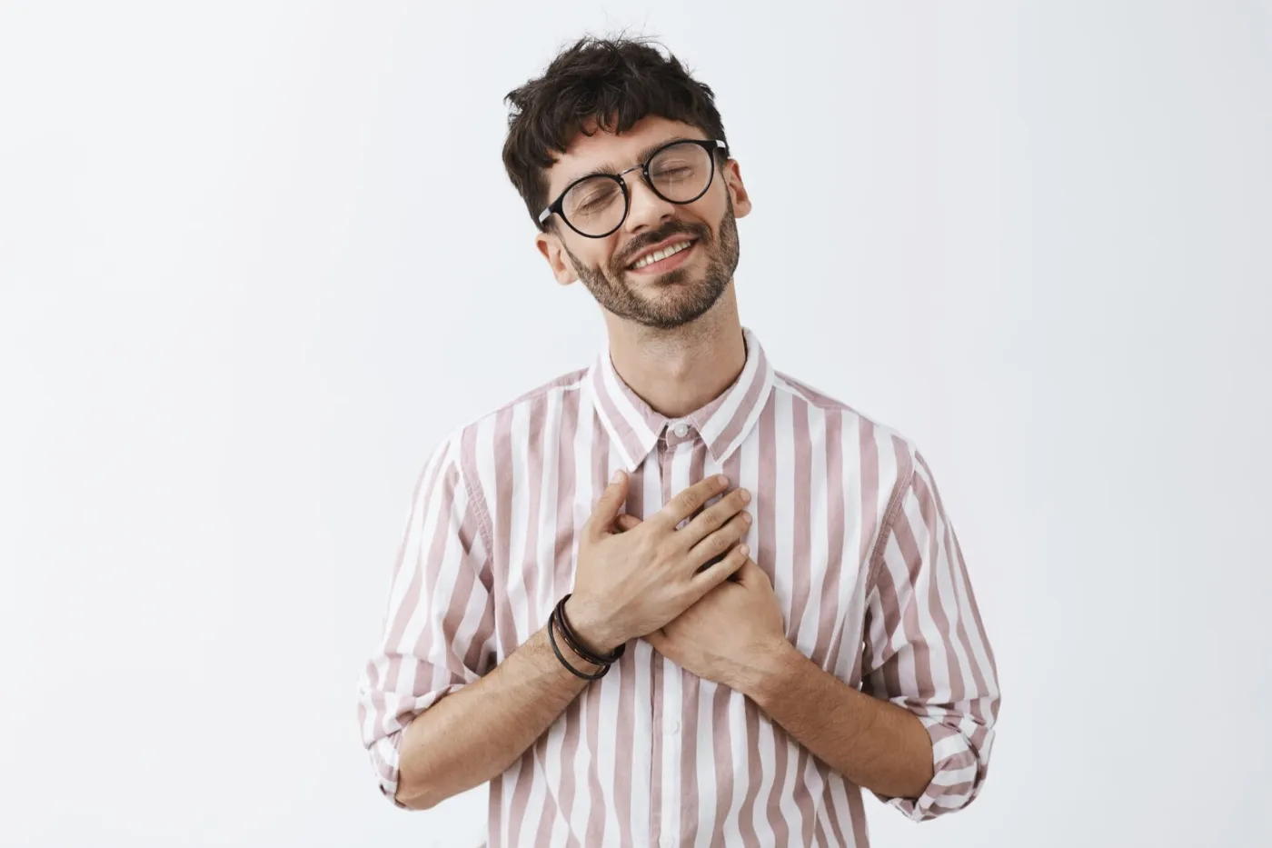 A smiling man in glasses with his hands on his chest