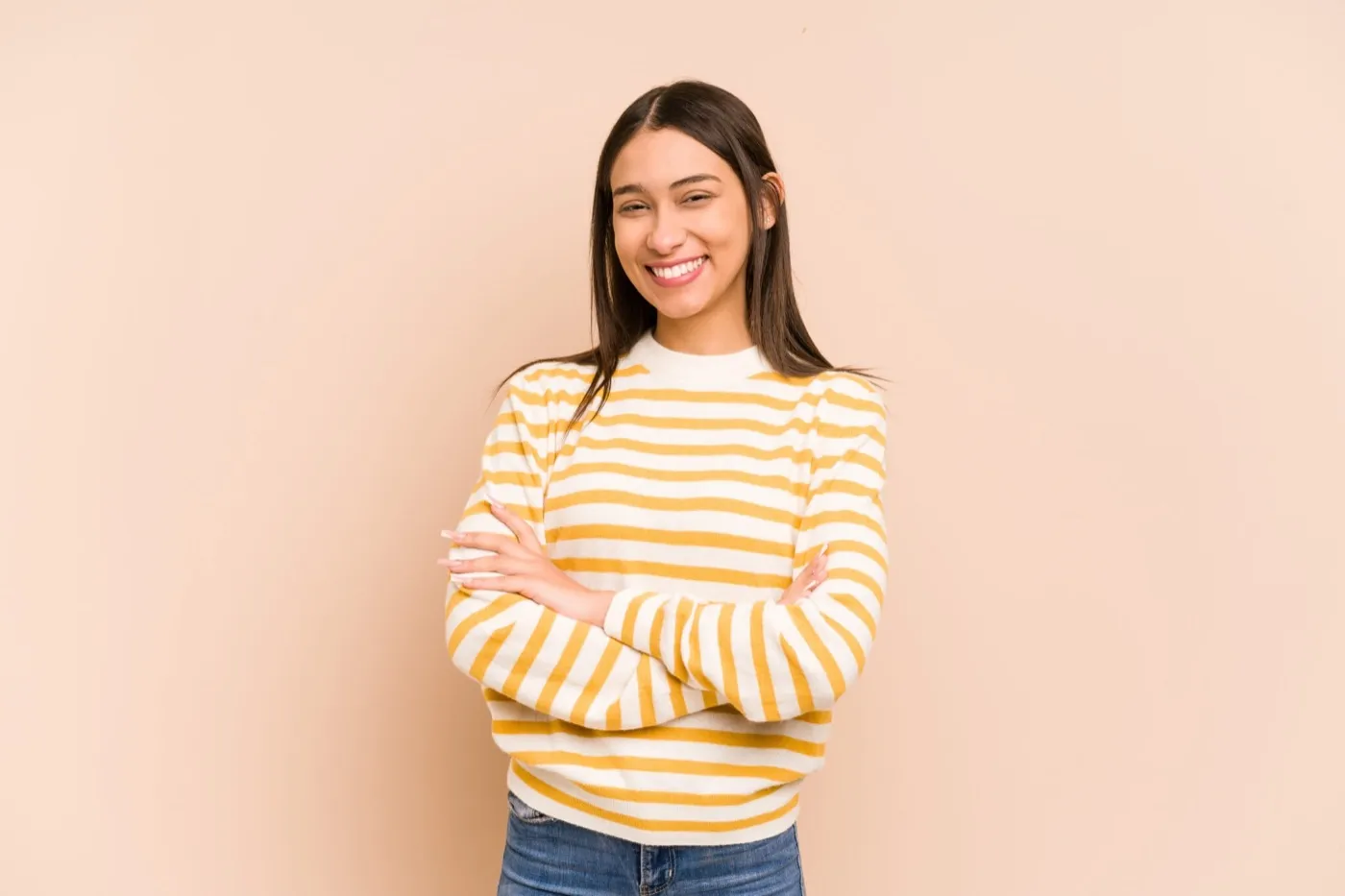 A smiling young woman in a striped jumper with her arms folded