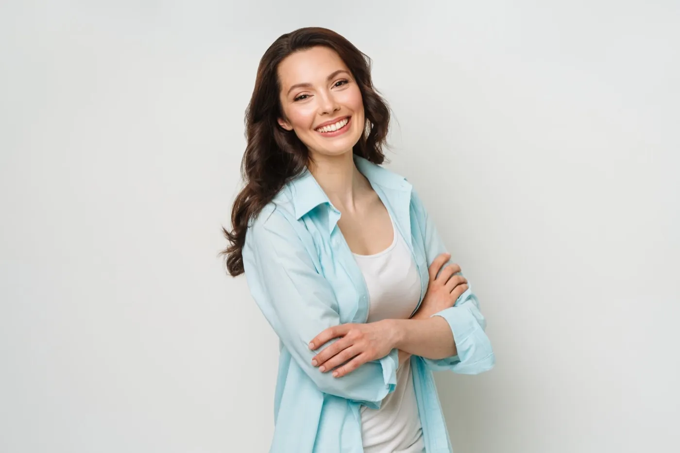 A smiling woman in a light blue shirt with her arms folded