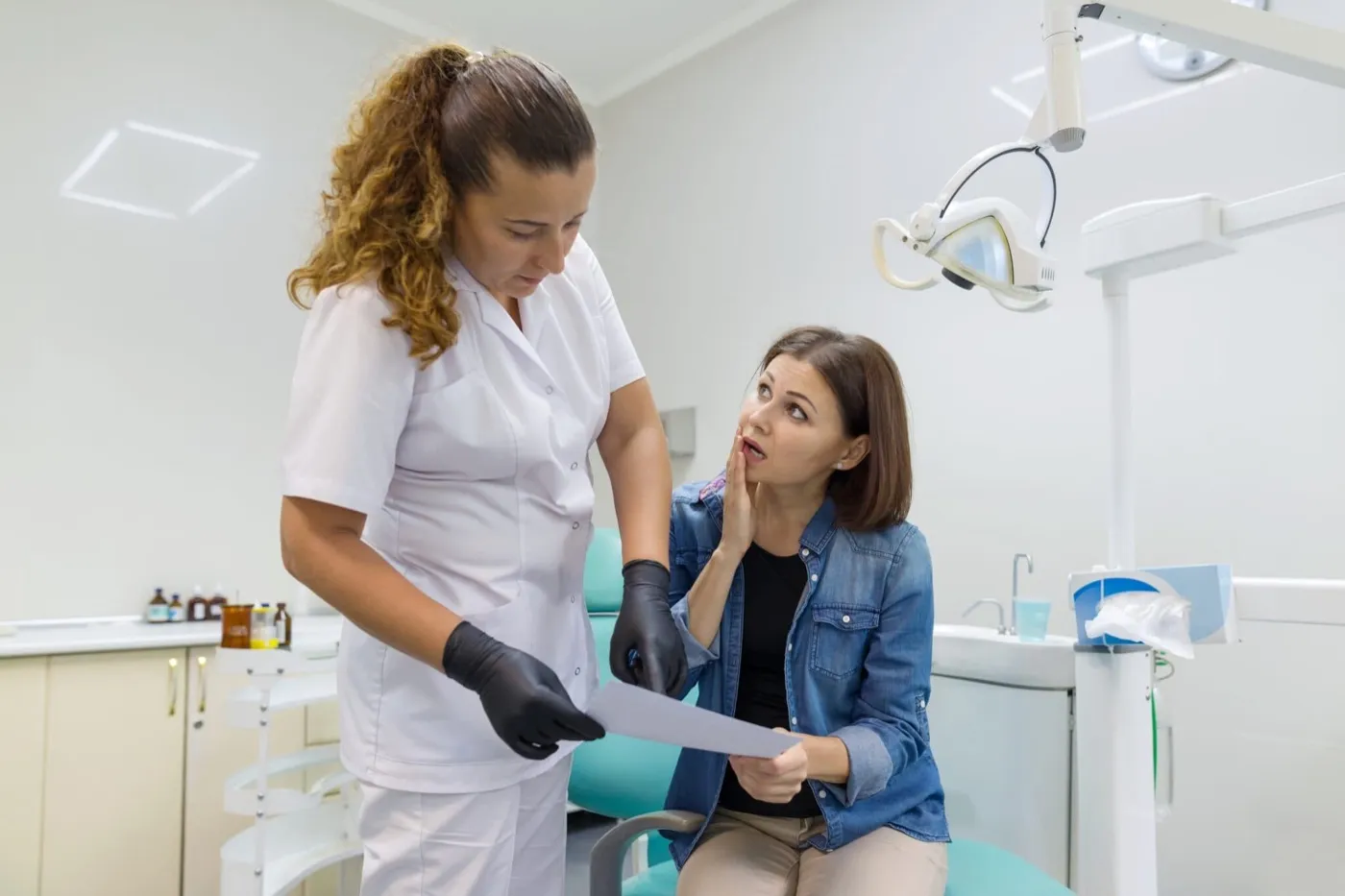 A dental nurse showing a document to a woman in the dental chair