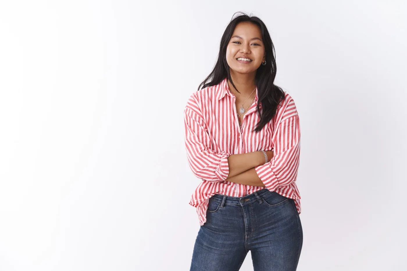 A smiling woman in a striped shirt with her arms folded