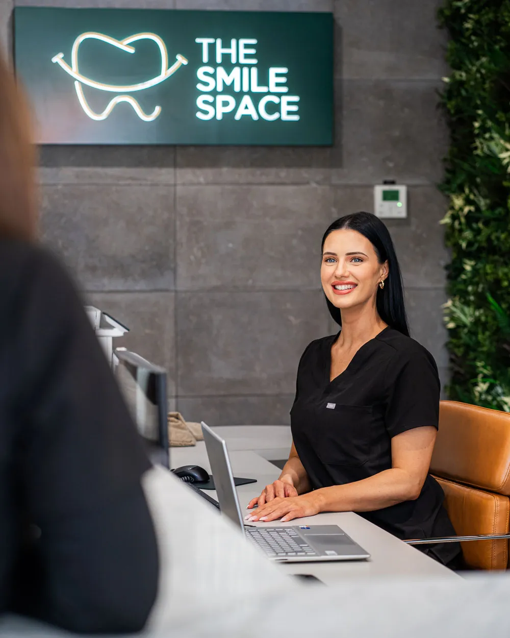 A receptionist smiling at the front desk, beneath The Smile Space sign
