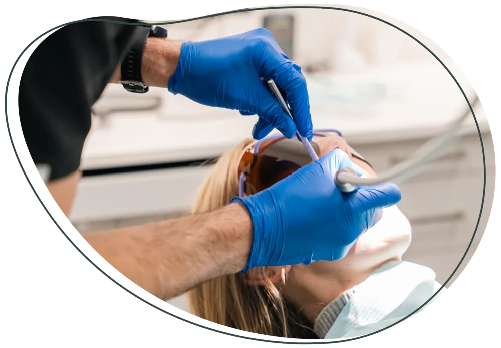 A dentist in blue gloves treating a patient