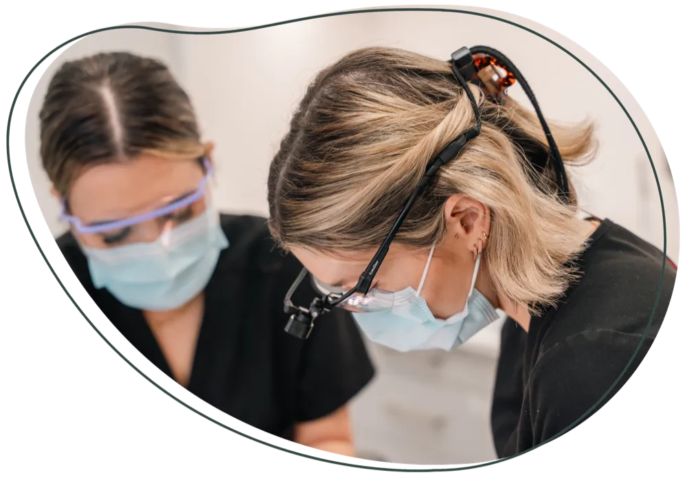 Two dental team members in masks and protective glasses