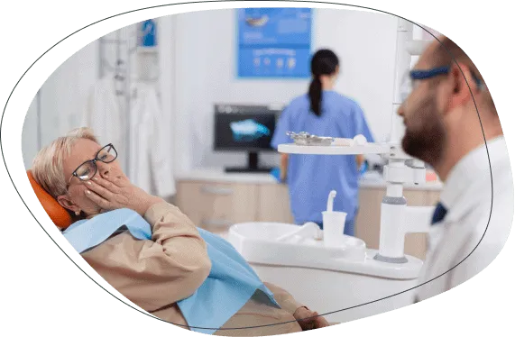 An older woman holding her jaw as she talks with a dentist