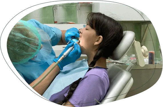 A dentist cleaning a young woman's teeth
