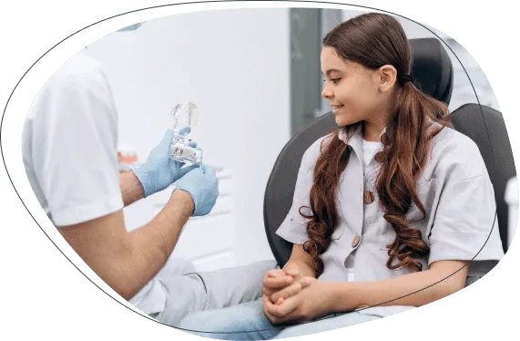 A dentist showing a girl a model of teeth
