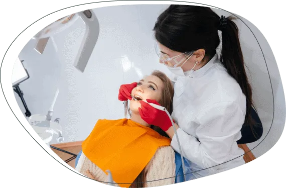 A dentist examining a woman's teeth in the treatment chair