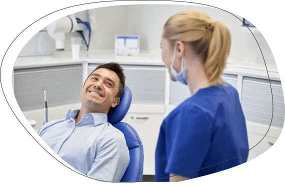 A smiling man in the treatment chair talking with a dental nurse