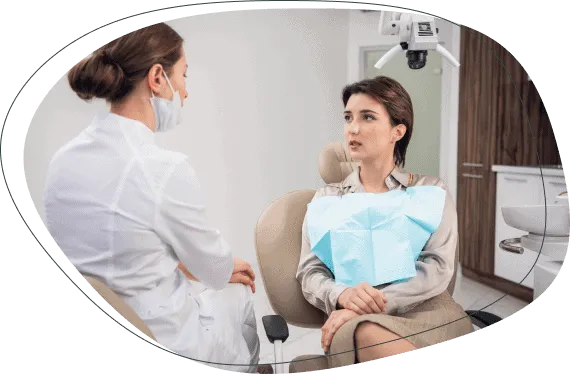 A dentist talking with a woman seated in the treatment chair