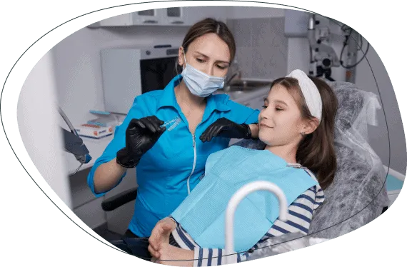 A dentist examining a girl's teeth in the treatment chair