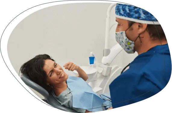 A smiling woman in the chair talking with her dentist