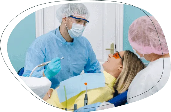 A dentist and a nurse treating a woman wearing protective glasses