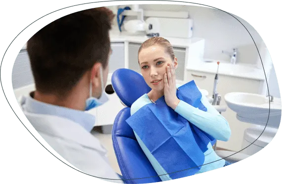 A woman in the chair holding her jaw while talking with a dentist