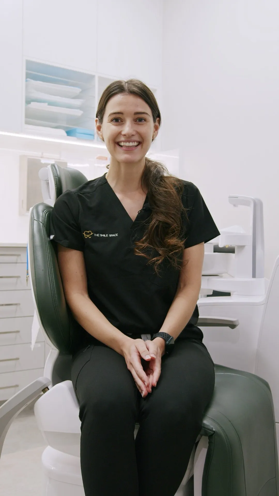 A smiling dentist seated in a dental chair