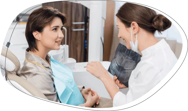 A dentist showing a patient an X-ray while she sits in the dental chair